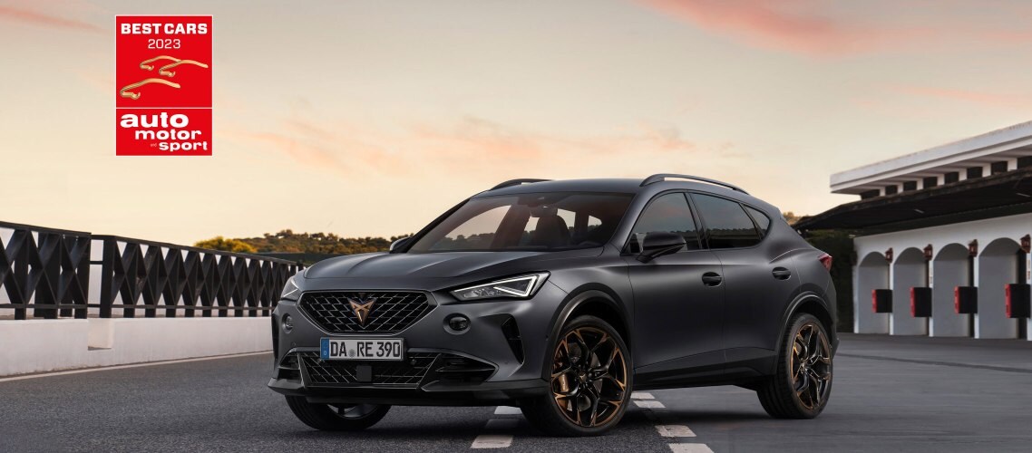 Der CUPRA Formentor Seitenabnsicht von vorne, stehend auf einer Brücke. Im Hintergrund ein Sonnenuntergang und die Auszeichnung Best Cars 2023.