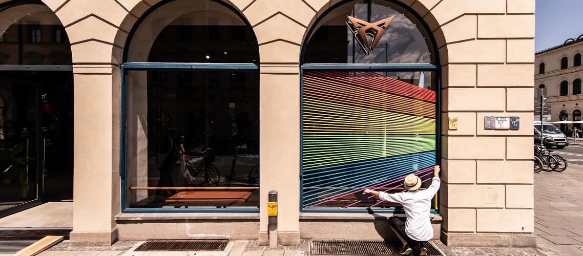 CUPRA City Garage in München mit den Regenbogenfarben auf den Fenstern. Außenansicht.