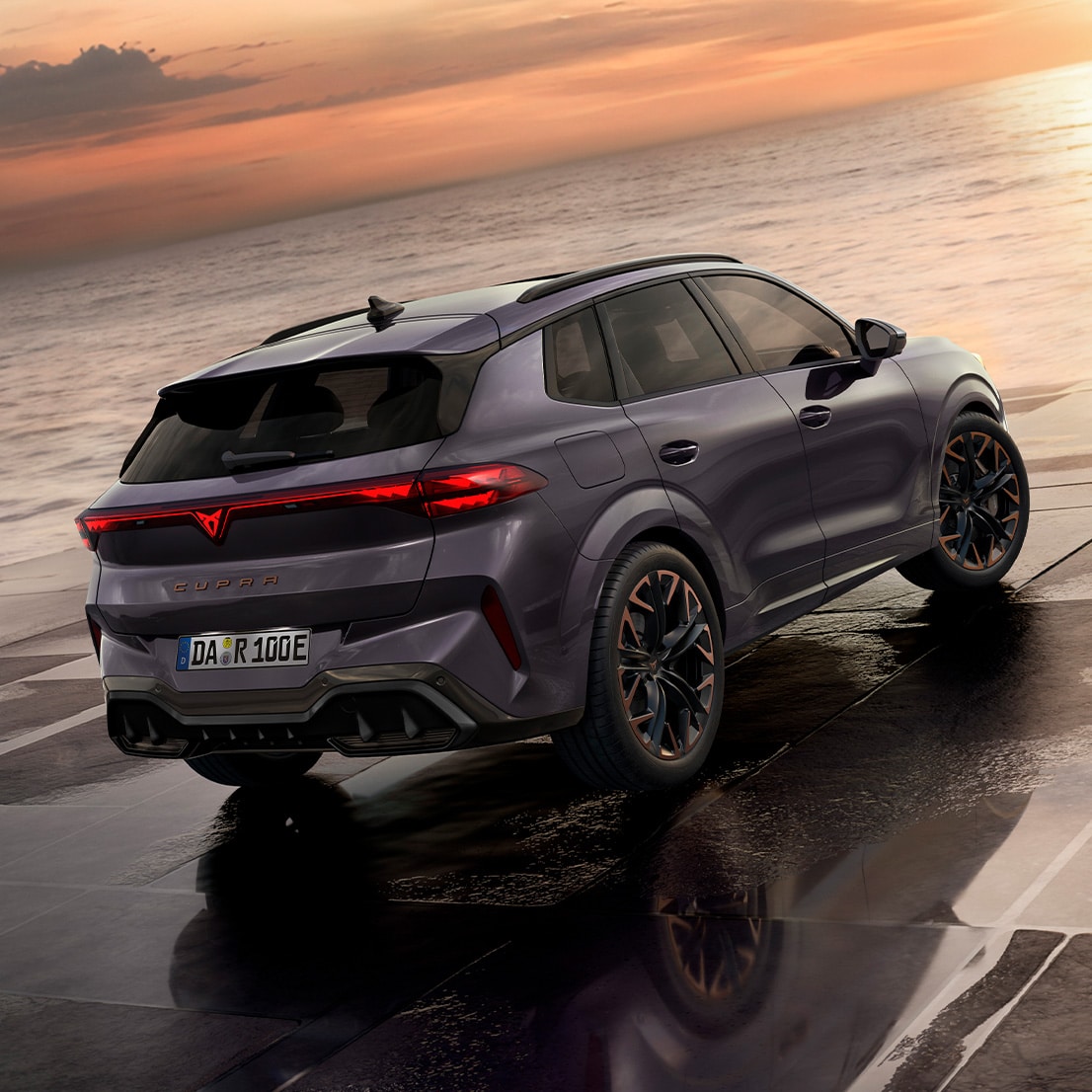 Seitenansicht eines CUPRA Fahrzeugs in Grau unter einer hellen Neon Röhre. Vor ihm stehen ein Mann und eine Frau und sehen in die Kamera.