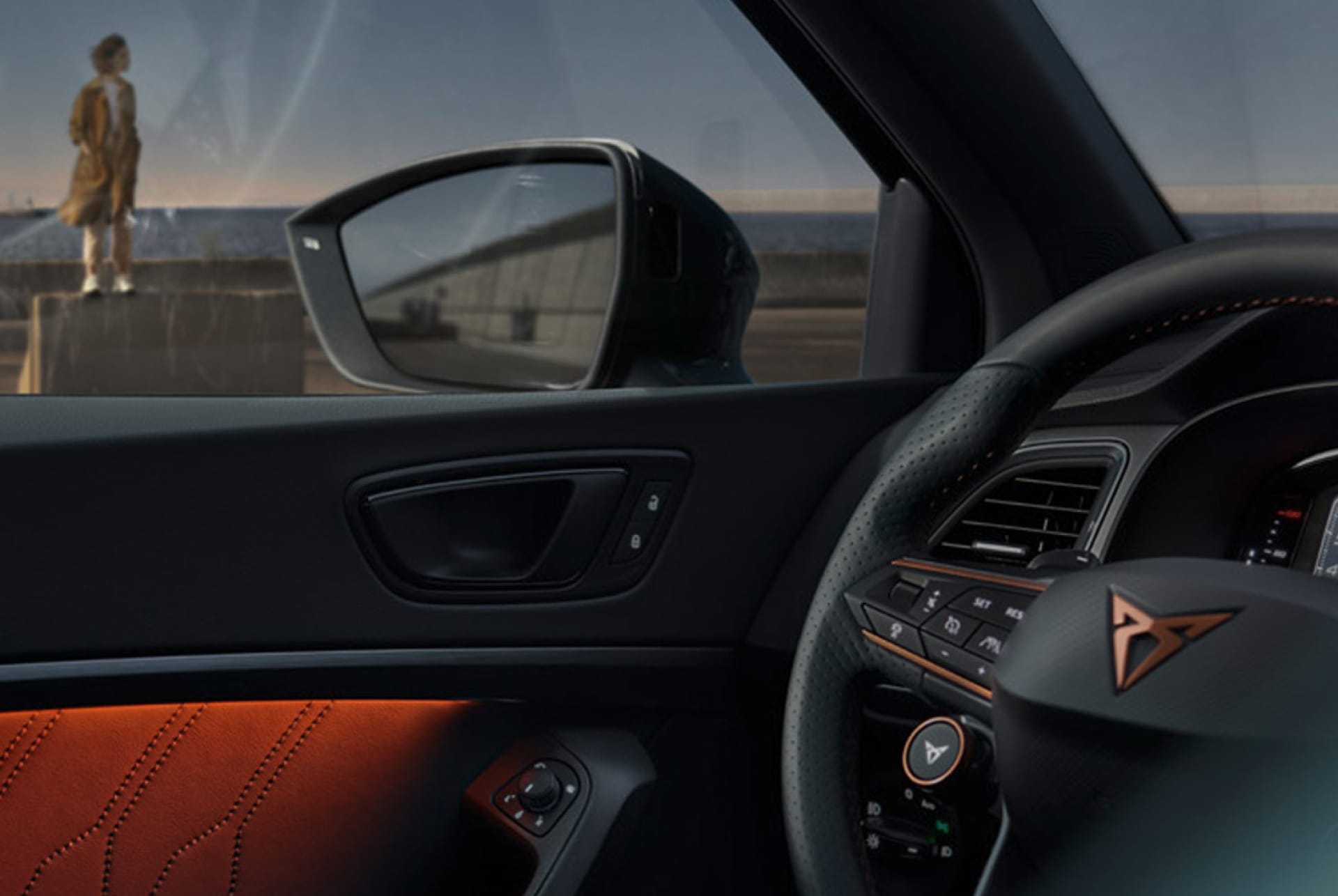 Innenansicht eines CUPRA Fahrzeuges auf der Fahrerseite. Man erkennt den linken Außenspiegel und die Hälfte des Lenkrads.