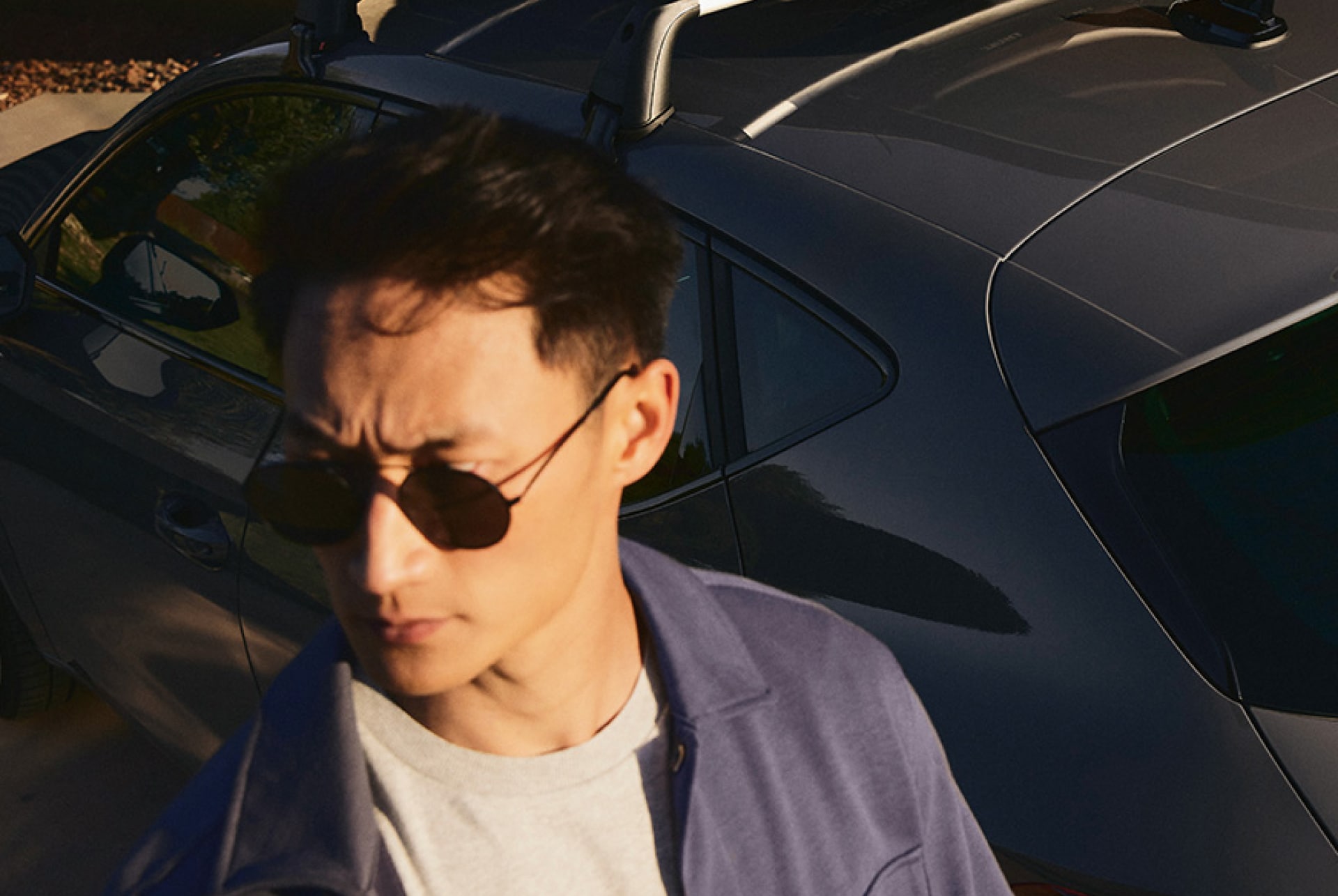 Stilvoll gekleideter Mann mit Sonnenbrille vor einem CUPRA Fahrzeug – urbaner Lifestyle trifft auf sportliches Design.