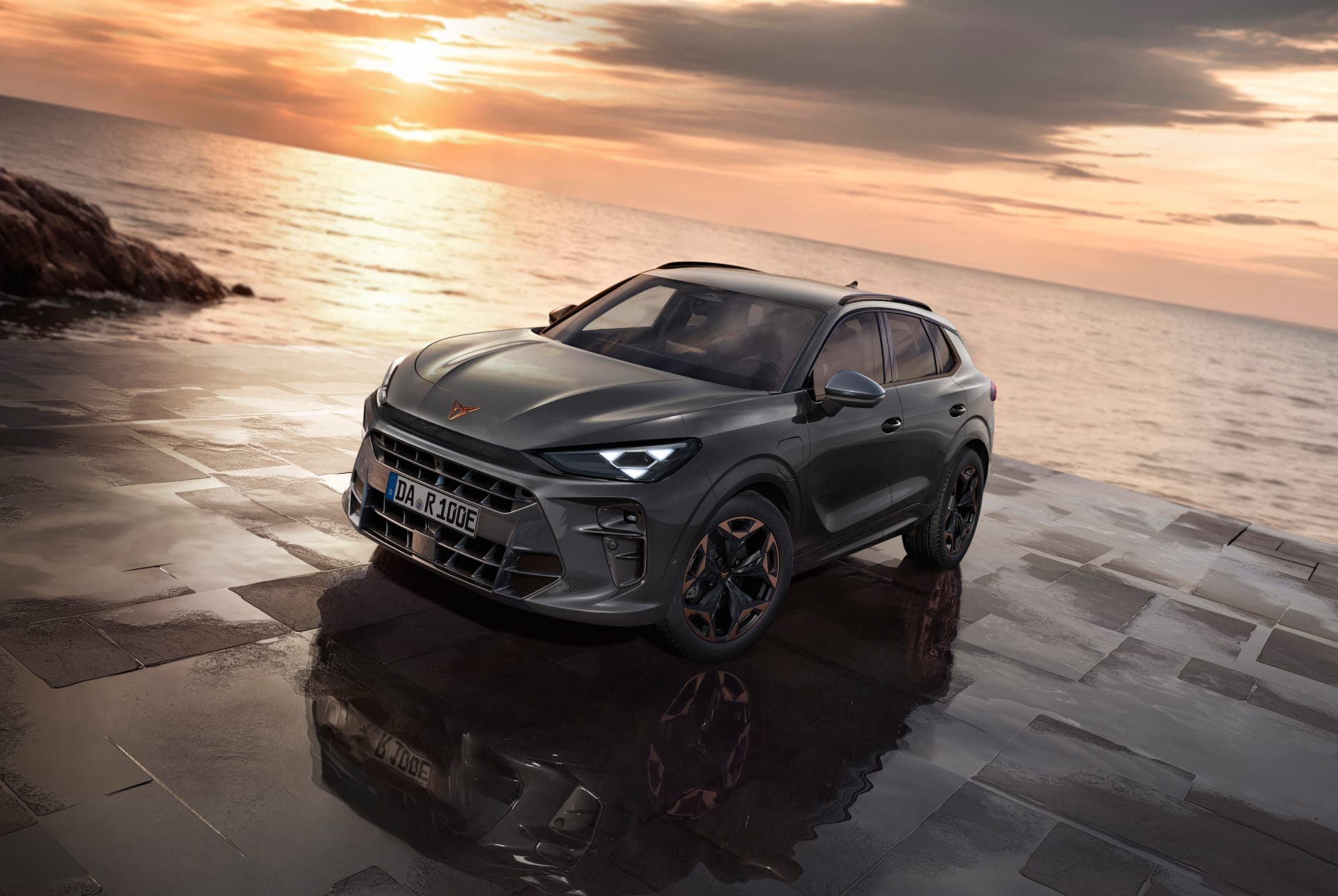 CUPRA Terramar von vorne oben, im Hintergrund das ruhige Meer und ein rosa Sonnenuntergang. Der nasse Boden reflektiert das Auto und verstärkt die eindrucksvolle Szenerie.