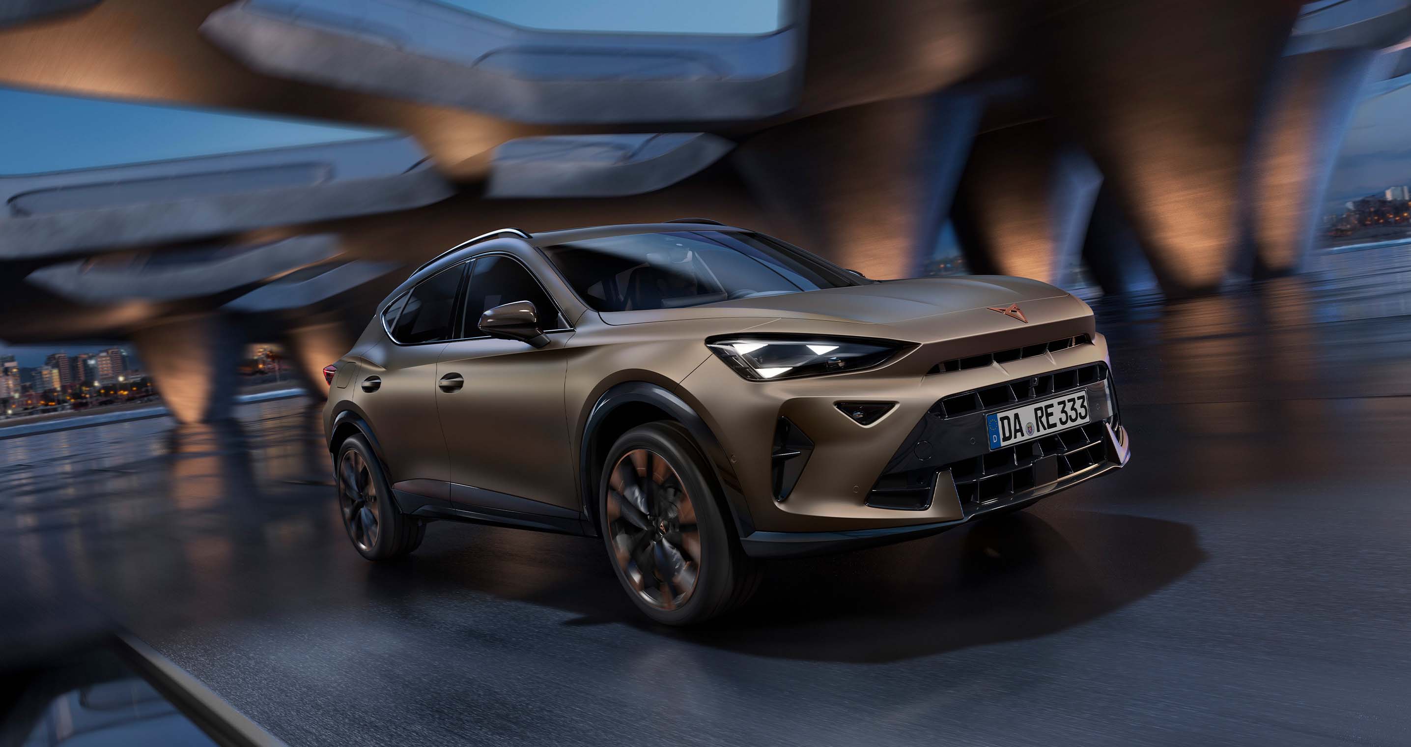 CUPRA Formentor in Bronze, mit Felgen in Kupfer. Der SUV fährt bei Abendlicht durch eine moderne architektonische Umgebung. Der Hintergund ist eine Stadt.