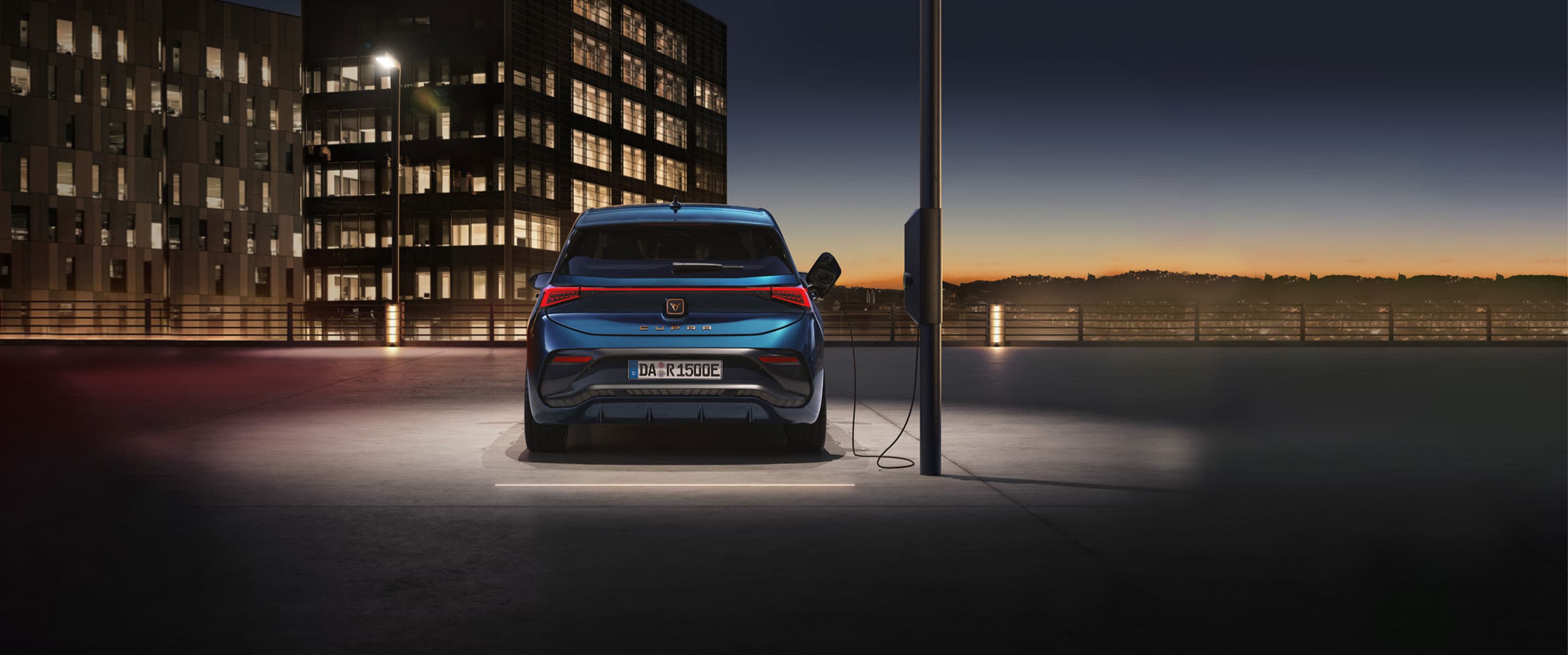 CUPRA Born, der an einer öffentlichen Ladestation angeschlossen ist, in minimaler und industrieller Umgebung.
