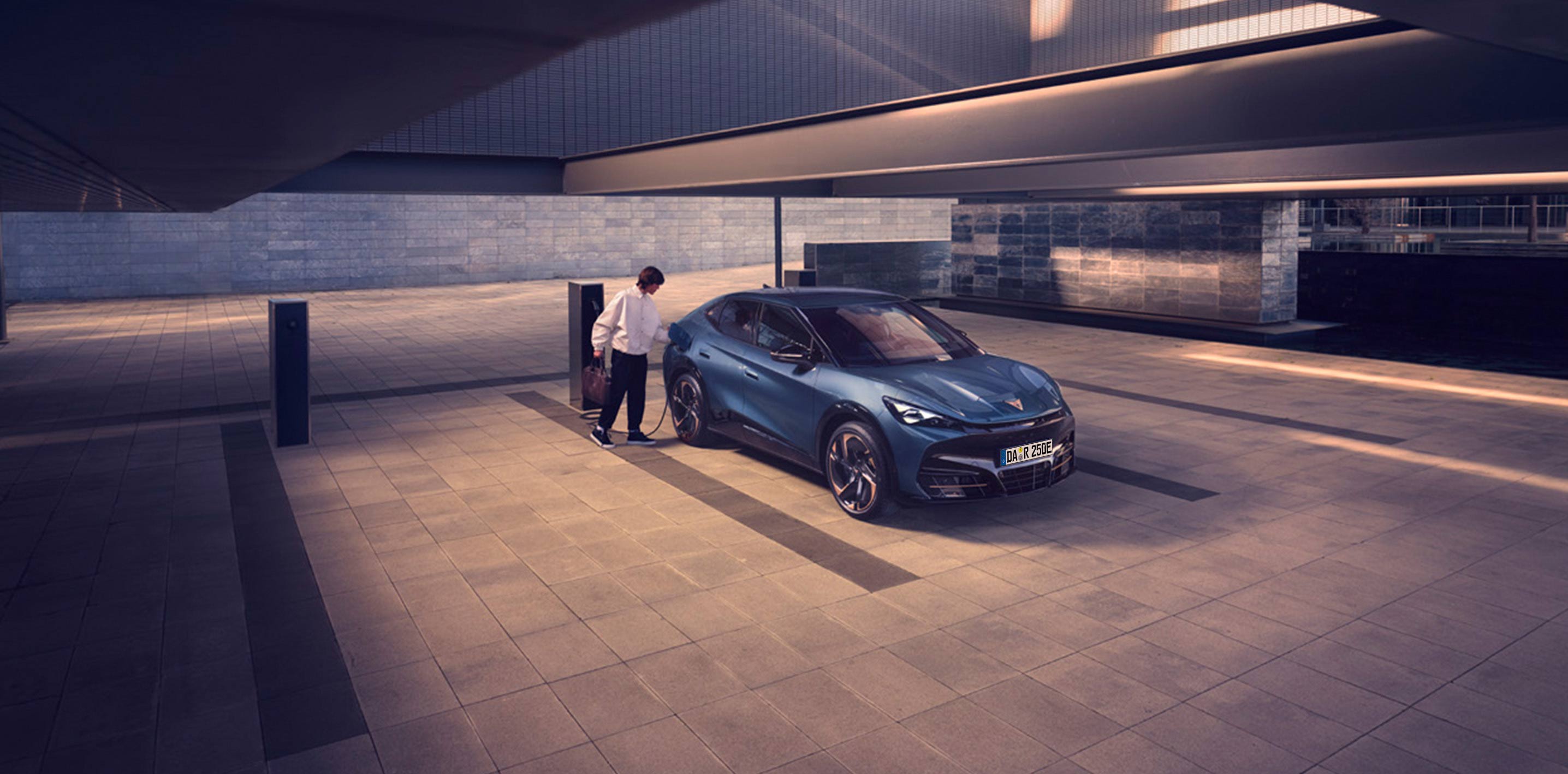 Ein CUPRA wird von einem Mann an einer öffentlichen Ladestation aufgeladen.