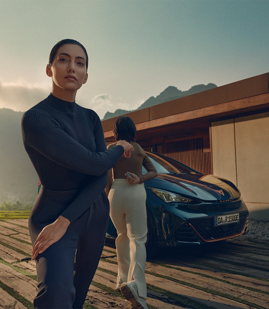 CUPRA Born in blau steht vor einem modernen Gebäude, Seitenansicht | CUPRA