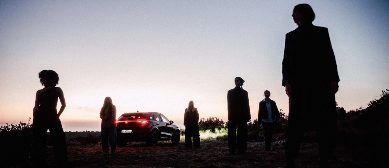 Mehrere Frauen stehen bei Sonnenuntergang in einer Landschaft, im Hintergrund ist ein CUPRA Terramar zu sehen.