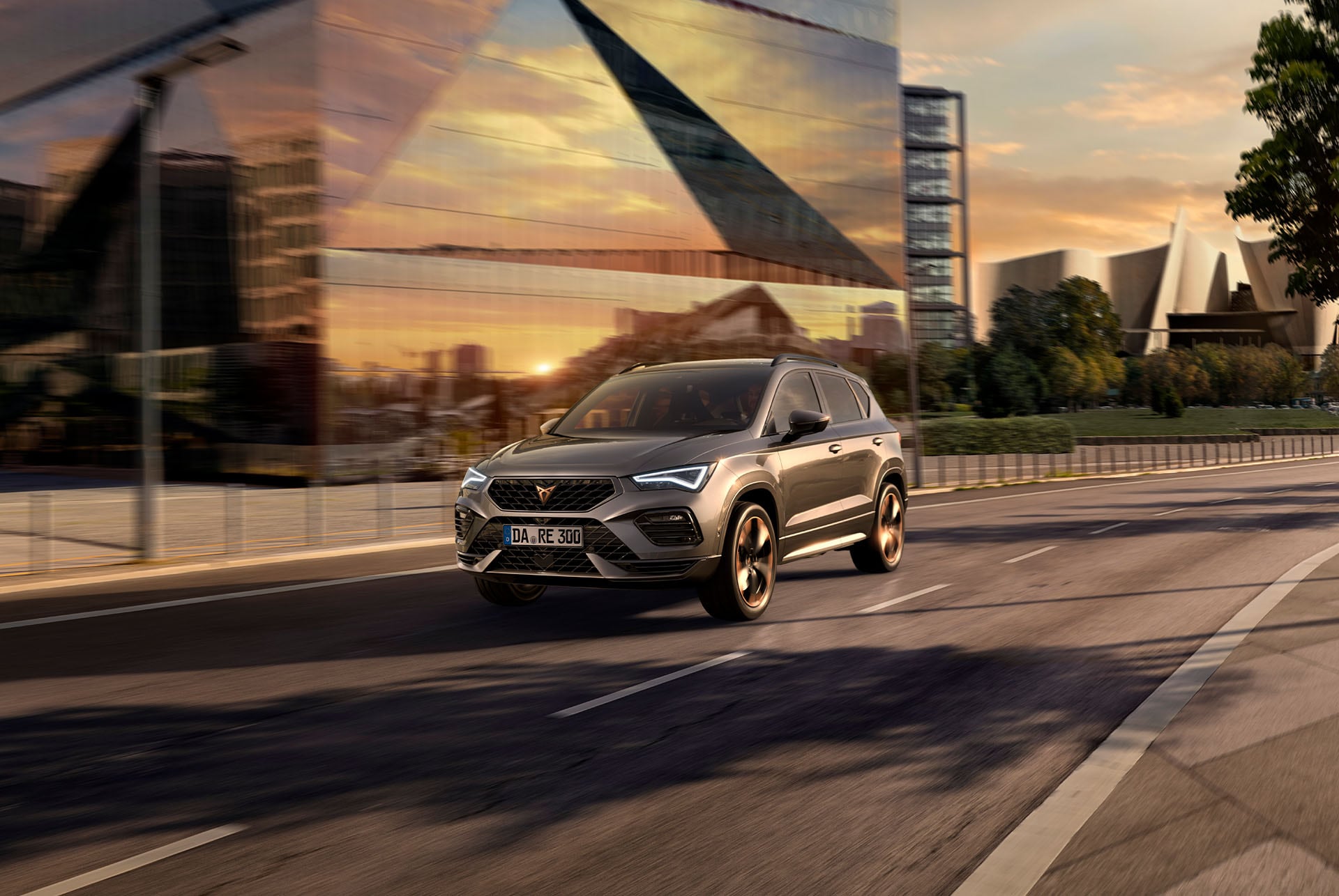 Der CUPRA Ateca SUV fährt bei Sonnenuntergang auf einer Stadtstraße. Der SUV ist mit Motoren in den Varianten 150 PS und 190 PS erhältlich, jeweils mit Allradantrieb, und bietet weniger Emissionen sowie einen reduzierten Kraftstoffverbrauch.