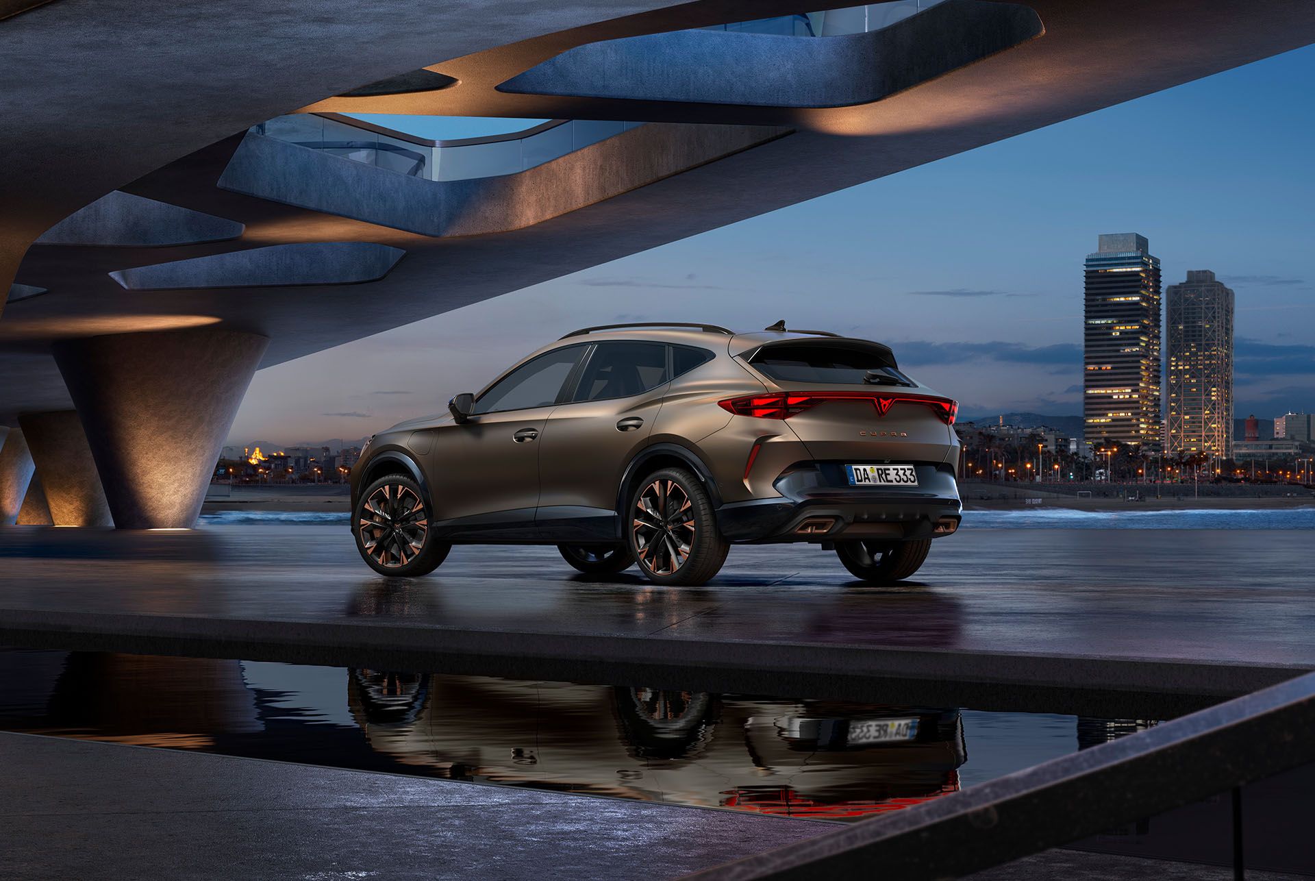 CUPRA Formentor in Century Bronze Matt, geparkt auf glattem Beton an einer Uferpromenade. Im Hintergrund die beleuchtete Skyline von Barcelona bei Dämmerung.