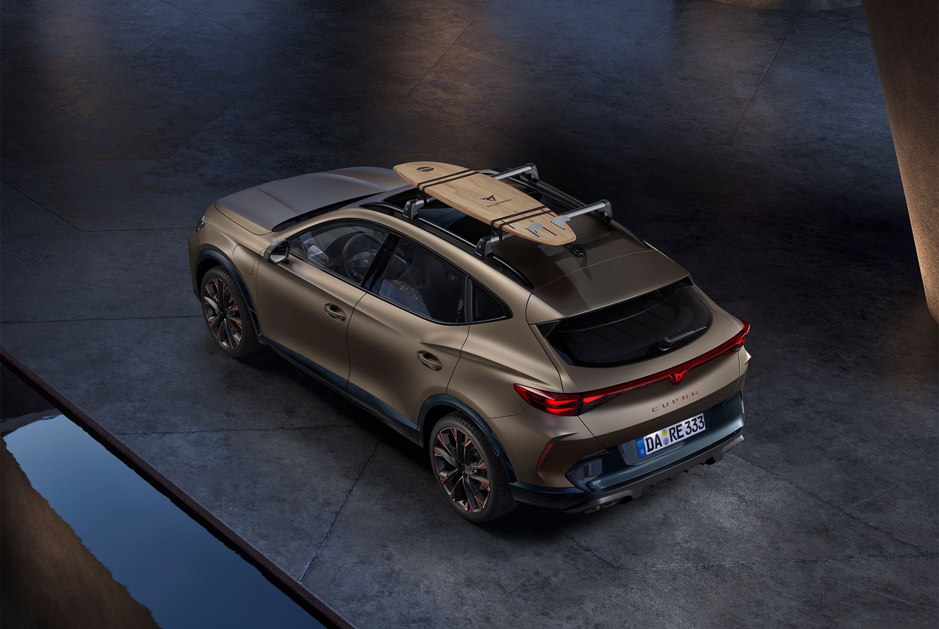 Vogelperspektive des CUPRA Formentor in Bronze Matt mit einem Surfbrett-Träger auf dem Autodach, das Auto ist auf Beton geparkt.