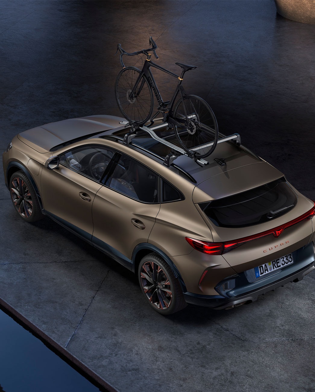 Blick aus der Vogelperspektive auf den CUPRA Formentor in Bronze Matt mit einem Fahrradträger, der in der Abenddämmerung auf dem Beton geparkt ist.