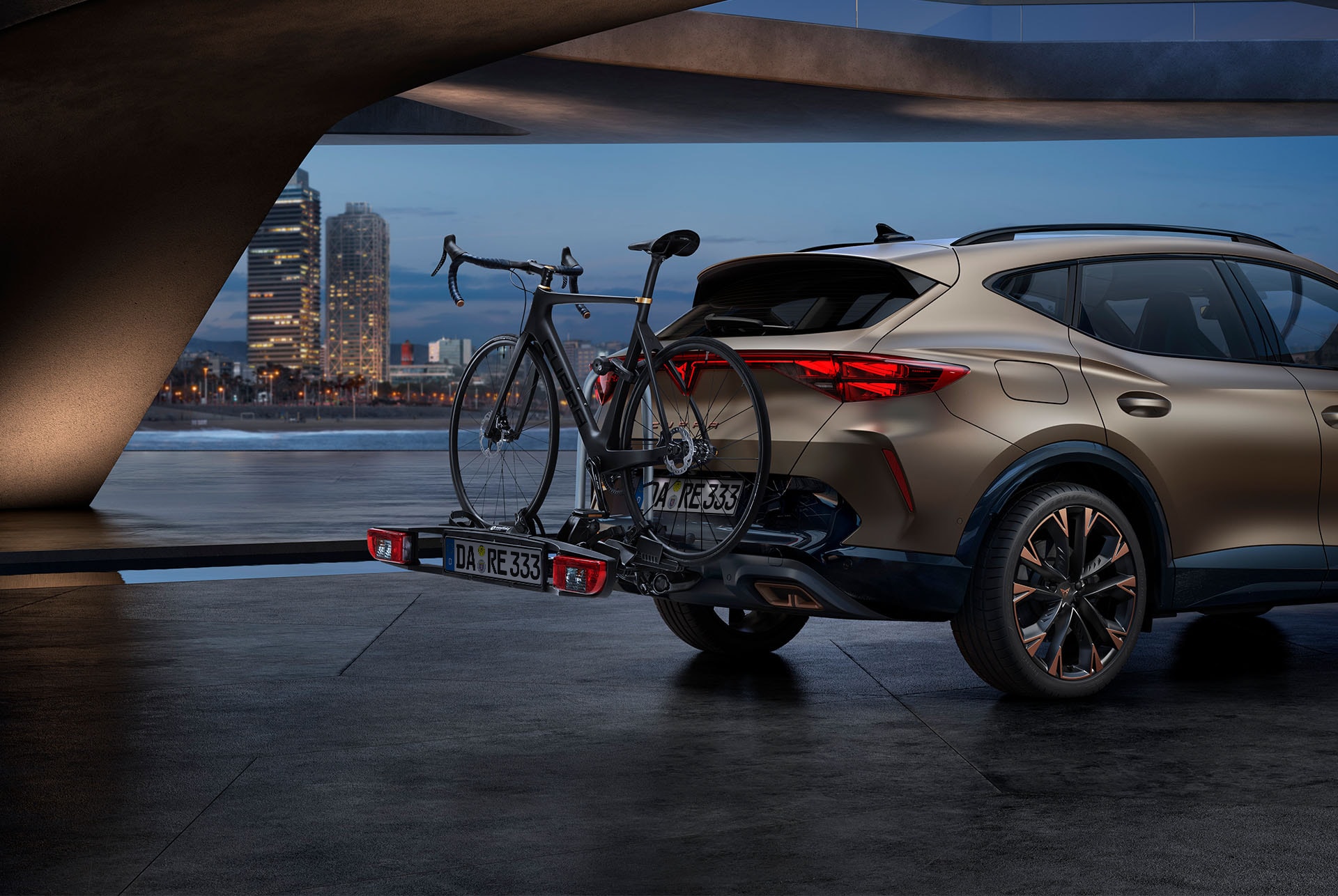 Der Bronze Matt CUPRA Formentor mit dem Heck- und Zugfahrradträger Autozubehör, Skyline der Stadt im Hintergrund.