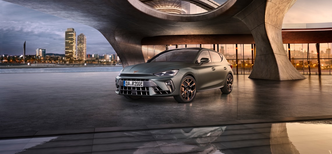 Der CUPRA Leon VZ Extreme in mattem Grau, präsentiert in einer futuristischen Architekturkulisse mit Blick auf die Skyline. Die aerodynamische Front mit dem markanten CUPRA-Logo und kupferfarbenen Felgen betont die rennsportliche DNA des Fahrzeugs.