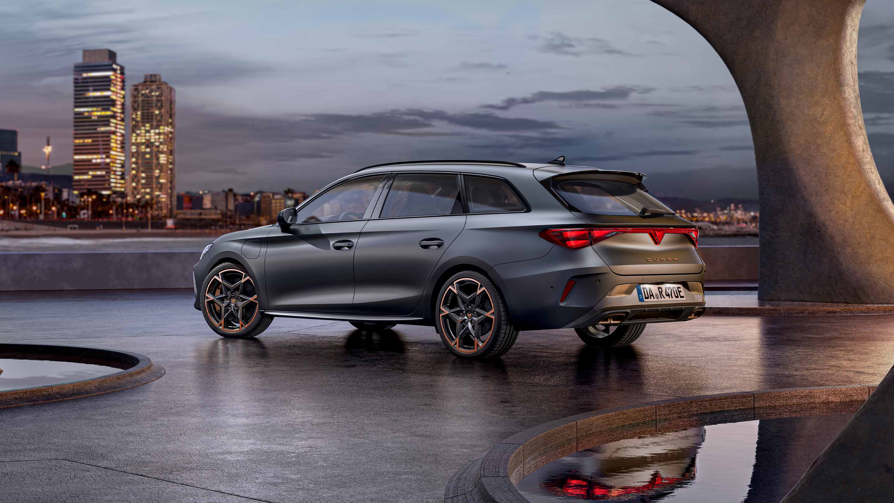 CUPRA Leon Sportstourer im Sonnenuntergang vor der Skyline von Barcelona. 