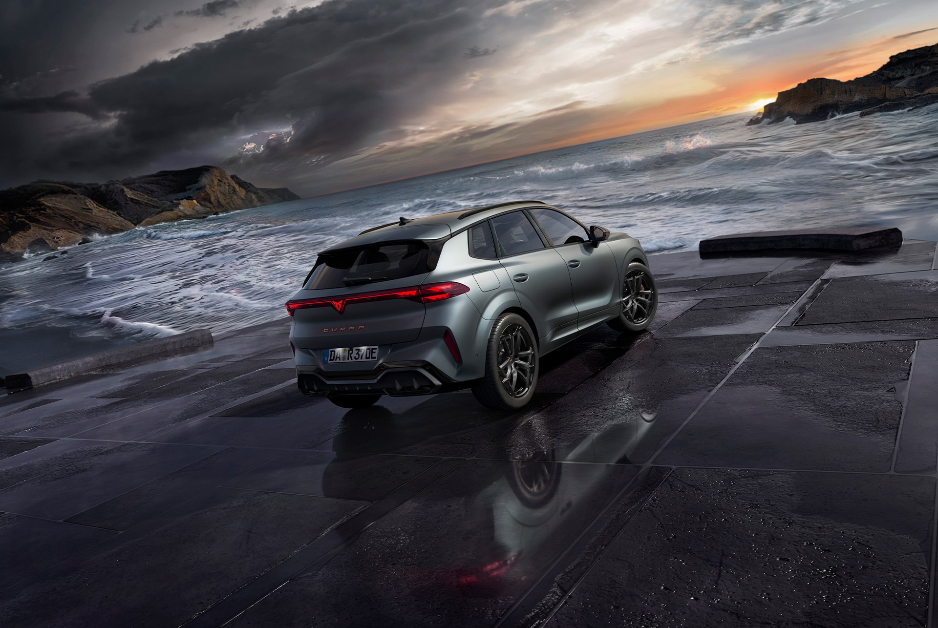 cupra terramar hybrid suv, modell 2024, rückansicht, mit schlanken rückleuchten mit cupra-logo, modernen leichtmetallrädern und einer sportlichen karosserie, auf einem nassen pflaster am meer.