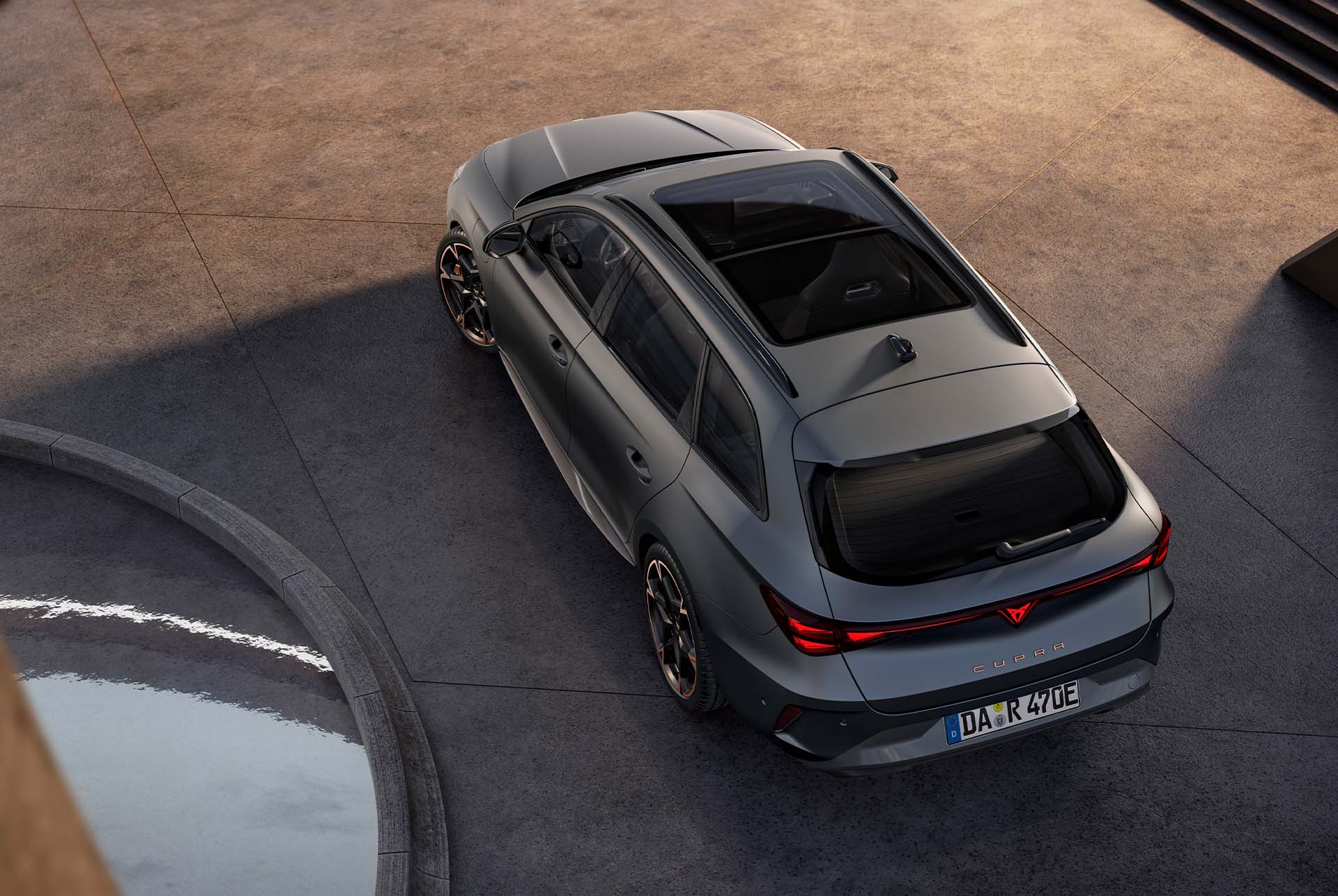  CUPRA Leon Sportstourer e-HYBRID, geparkt auf Beton, mit Panorama-Schiebedach, elektrischer Heckklappe und markantem Design aus der Vogelperspektive.