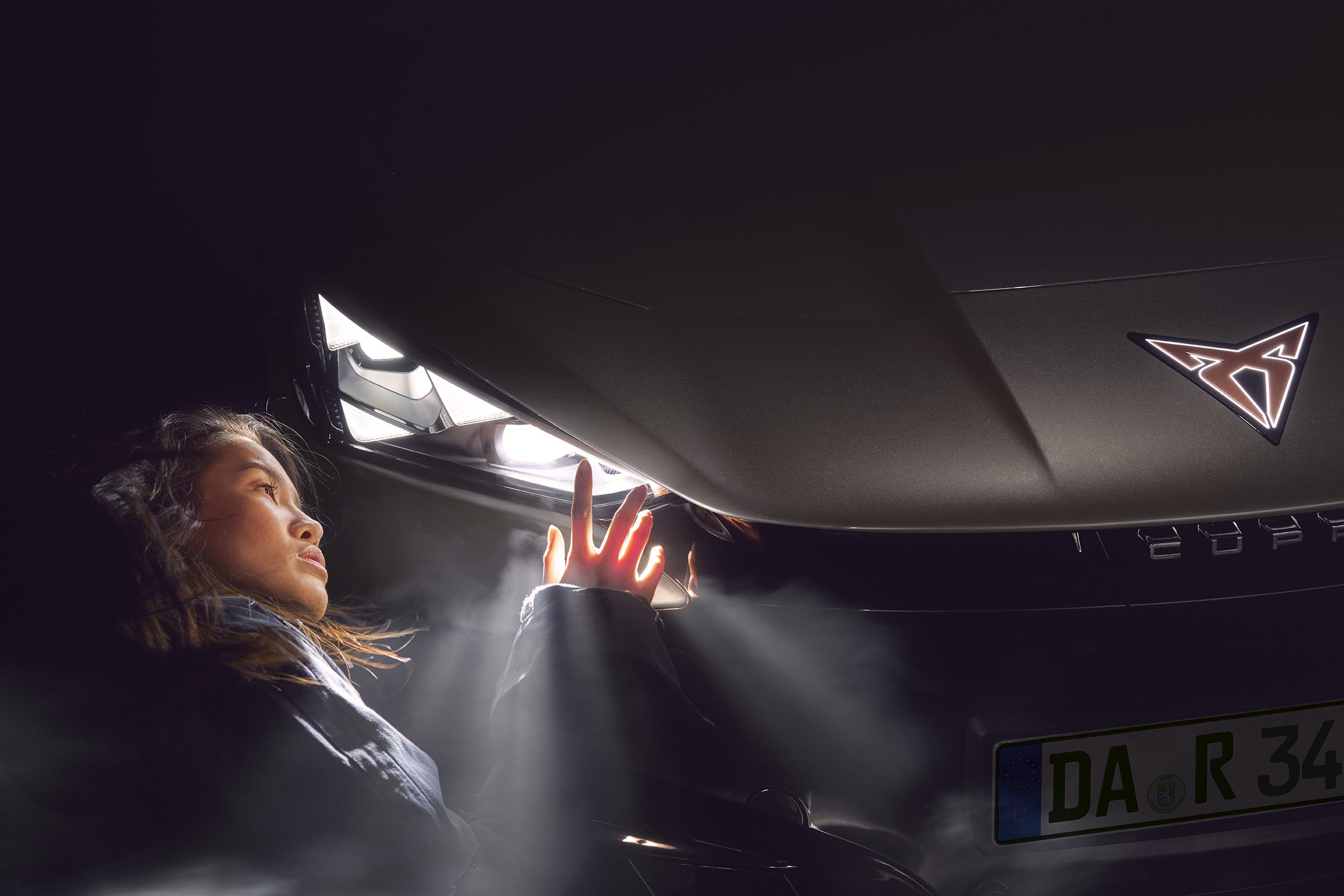 Frau schaut auf Scheinwerfer des CUPRA Tavascan