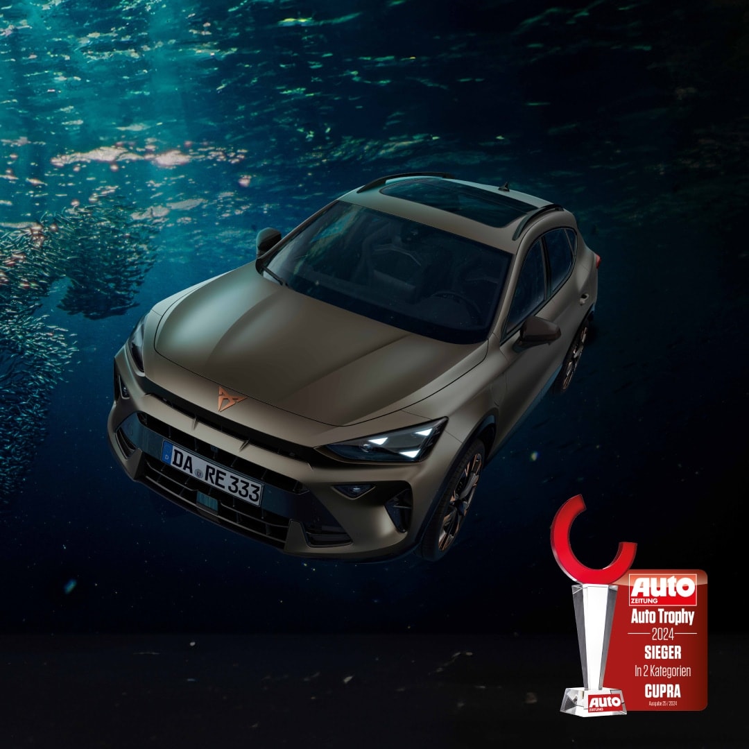 Der CUPRA Formentor in mattem Bronze im Meer unter der Wasseroberfläche, daneben die Auto Trophy 2024-Trophäe mit rotem Halbkreis auf silbernem Sockel.