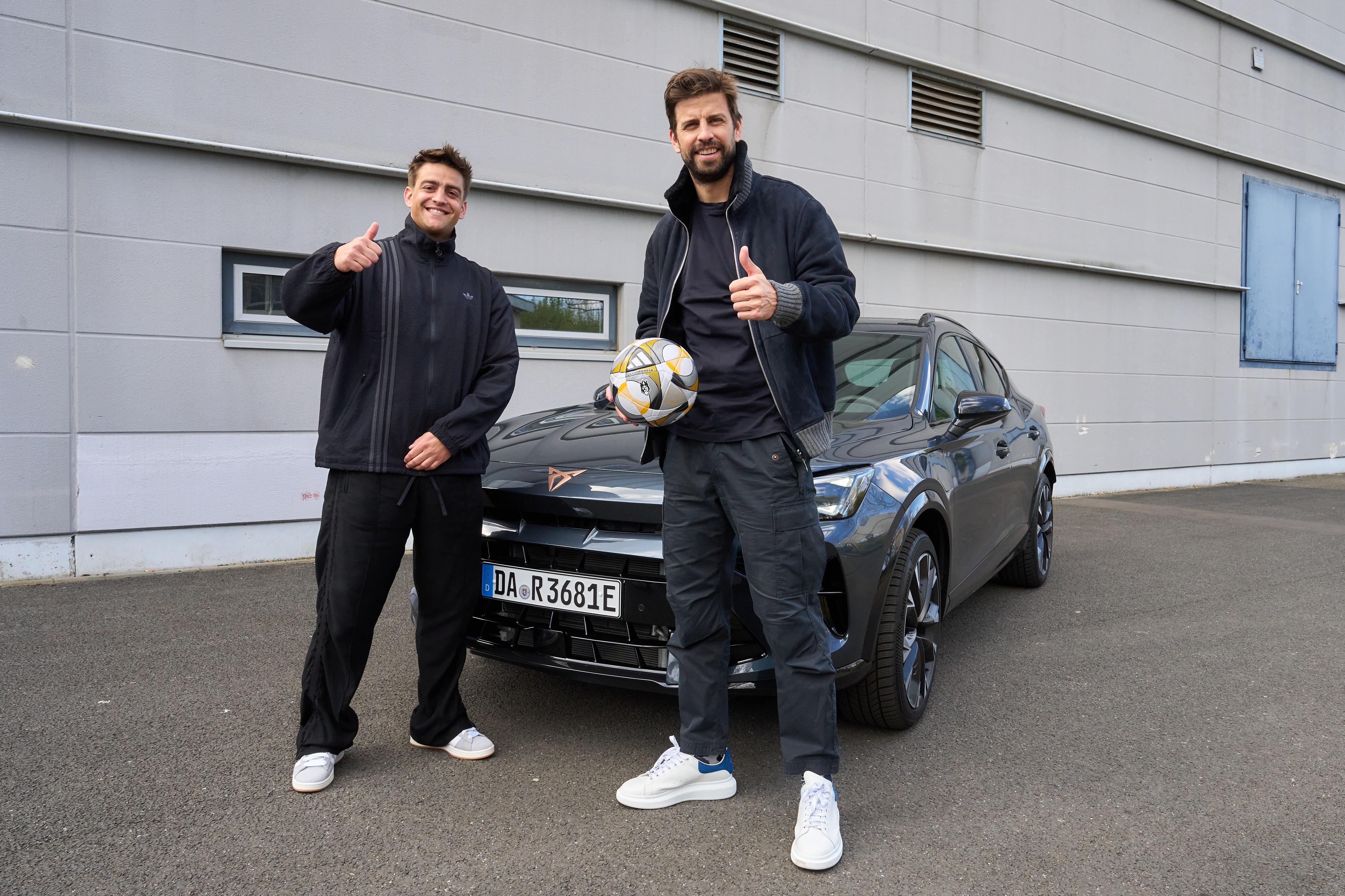 Paul Frege und Gerard Piqué stehen vor einem CUPRA Formentor. Piqué hält einen Fußball in der Hand, beide zeigen einen Daumen nach oben.