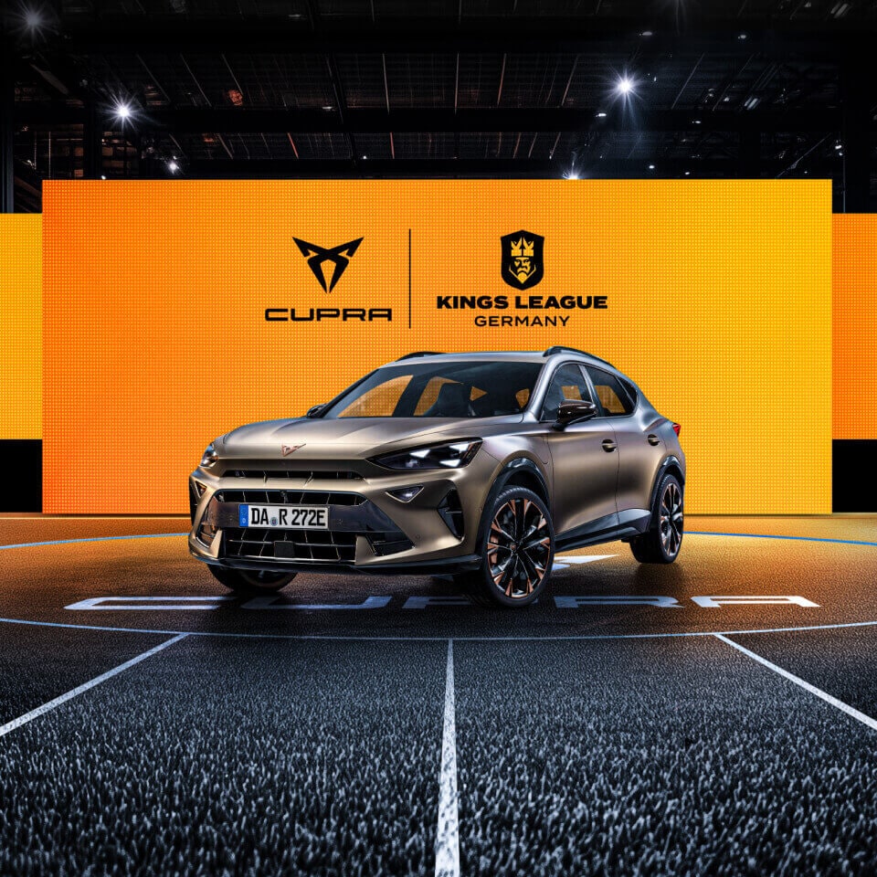 CUPRA Formentor e-HYBRID vor einer Wand aus Screens mit dem CUPRA Logo und dem Kings League Germany Logo. Der CUPRA Formentor e-HYBRID steht im Mittelkreis eines Spielfelds der Kings League.