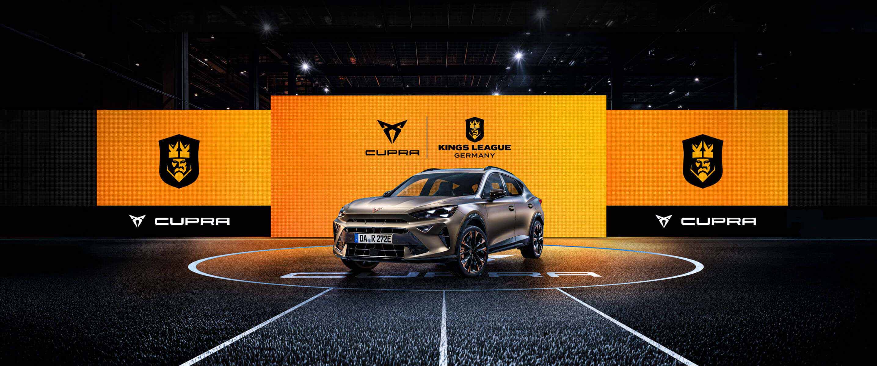 CUPRA Formentor e-HYBRID vor einer Wand aus Screens mit dem CUPRA Logo und dem Kings League Germany Logo. Der CUPRA Formentor e-HYBRID steht im Mittelkreis eines Spielfelds der Kings League.
