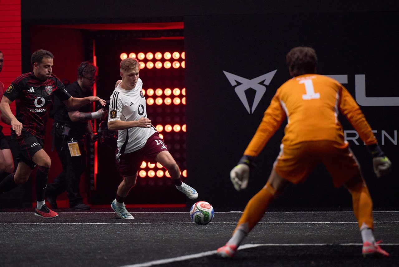 Intensiver Zweikampf zwischen drei Spielern vor leuchtender CUPRA Branding-Wand bei der Kings League.