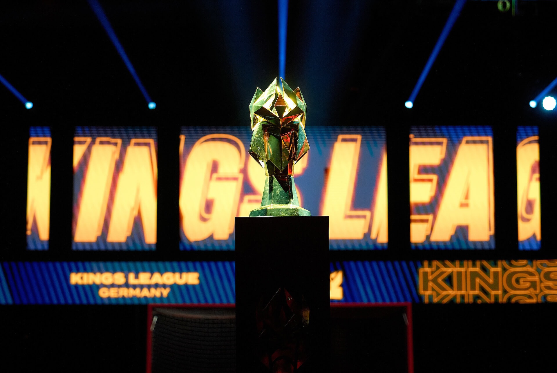 Kings League Pokal steht vor einer Wand aus Bildschirmen mit dem Schriftzug Kings League Germany