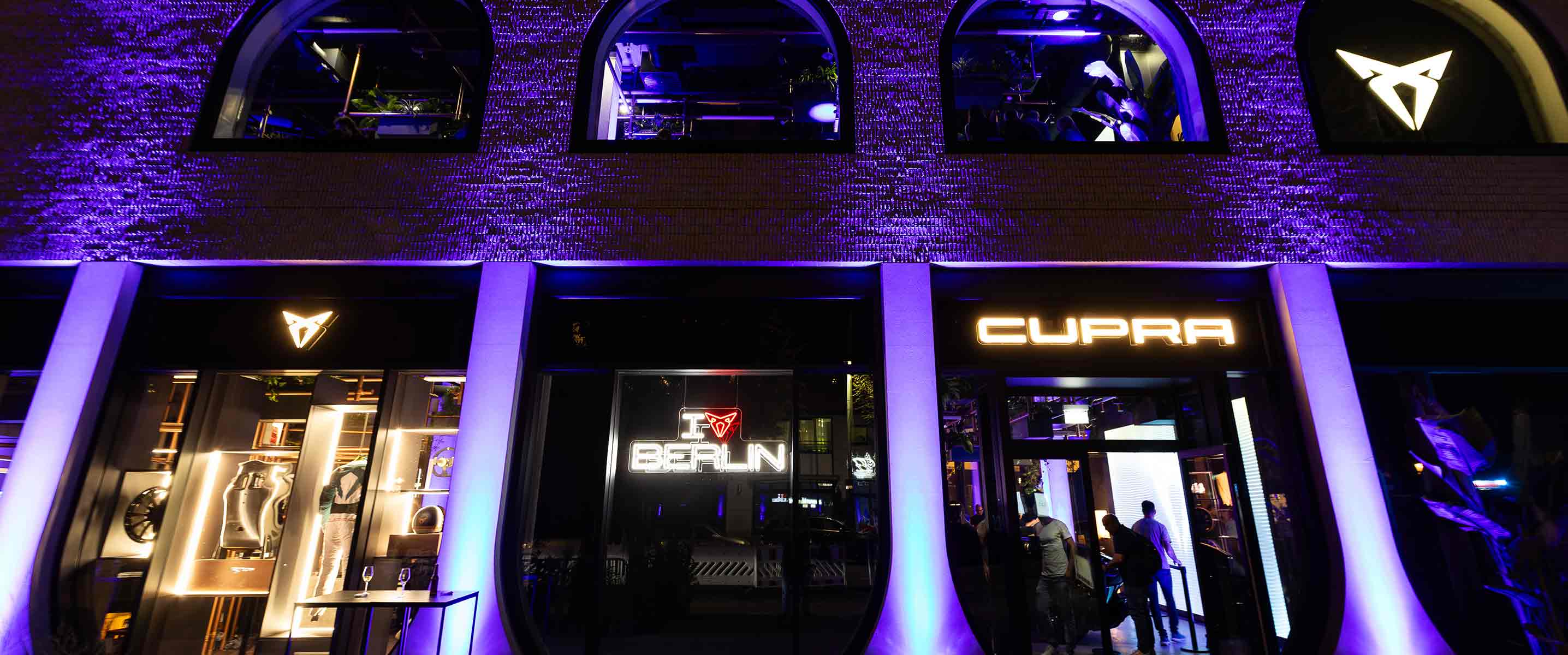 Eröffnung der CUPRA CITY GARAGE in Berlin. Außenansicht des Gebäudes lila erleuchtet. 