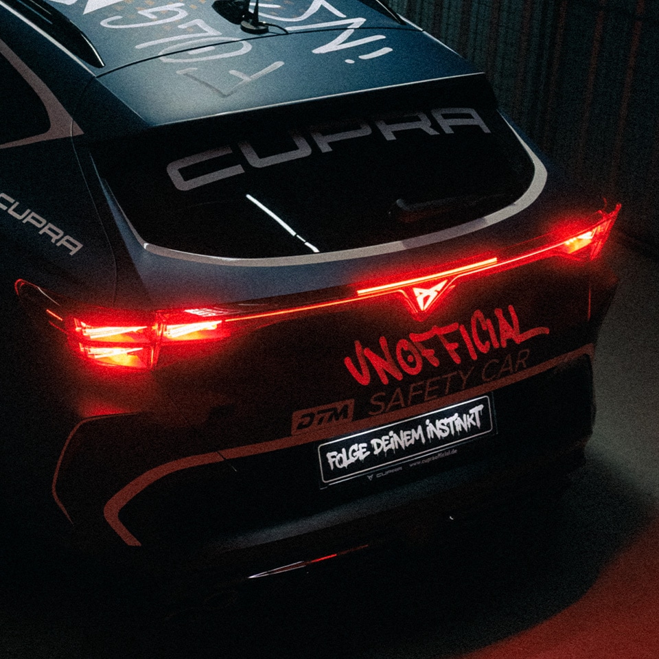 Heckansicht eines CUPRA Formentor bei Nacht mit leuchtenden Rückleuchten und Graffiti-Schriftzug »Unofficial – Folge deinem Instinkt«