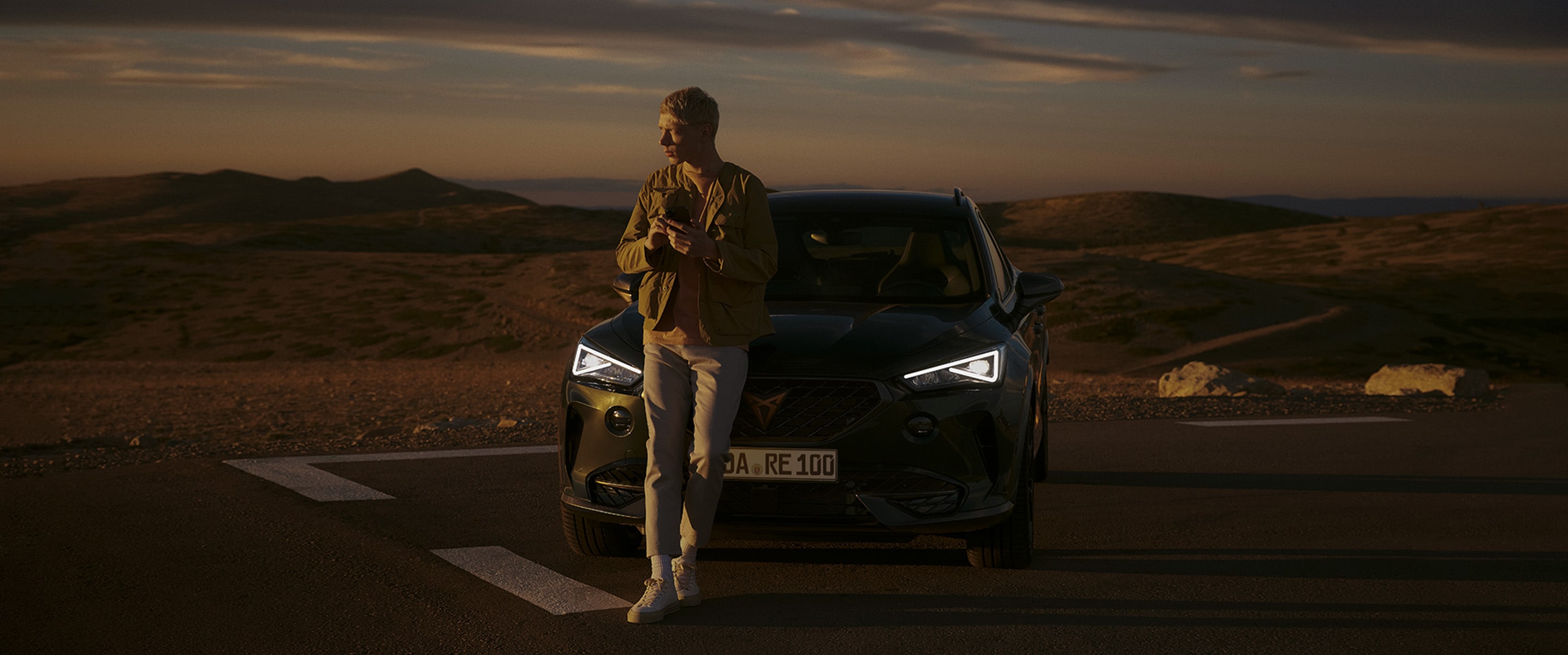 man-in-front-of-cupra-formentor-dark-camouflage-with-mobile-in-the-dessert