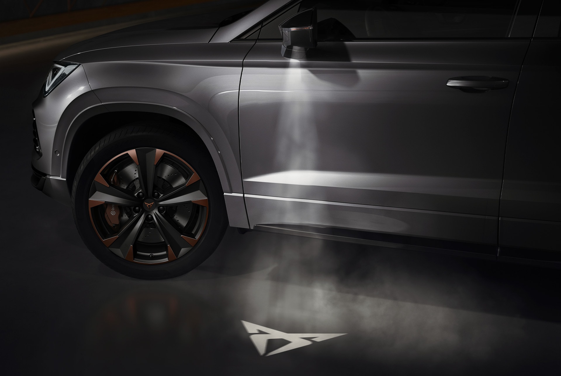 Das CUPRA-Logo, das vom CUPRA Ateca auf den Boden projiziert wird, und die Verbindung mit dem CUPRA Tribe symbolisiert.