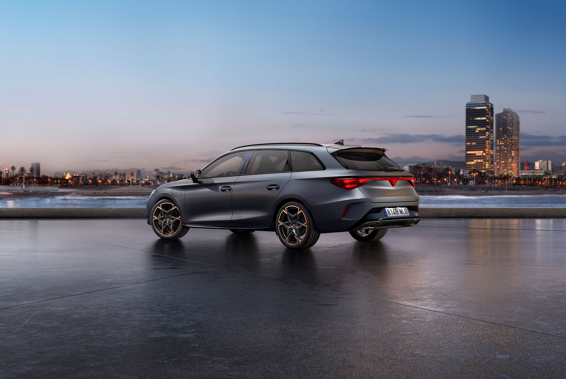 Der sportliche CUPRA Leon Sportstourer, geparkt auf Beton, mit einer beleuchteten Stadtsilhouette in der Dämmerung im Hintergrund. Das Fahrzeug wird in mattem Grau dargestellt.