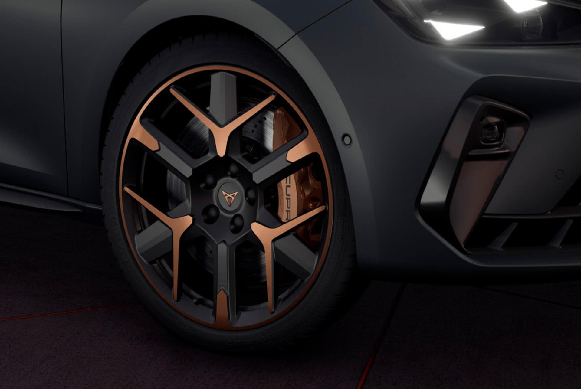  CUPRA Leon Sportstourer, Nahaufnahme von Kupfer-Akzent, schwarzen Rädern und CUPRA-Scheinwerfern in Dreiecksform, mit Karosserie in Enceladus Grey Matt.