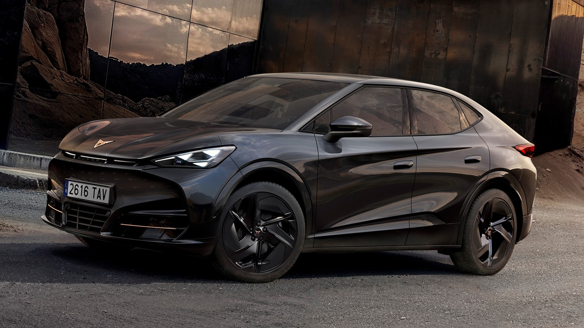 Hero Shot: 3/4-Vorderansicht des CUPRA Tavascan Black Edition, geparkt in felsiger Umgebung mit Außendetails wie schwarzen Katla 21-Zoll-Leichtmetallrädern.