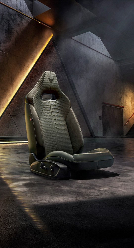 Ein grauer CUPRA Fahrzeugsitz steht in einer leeren Halle. 